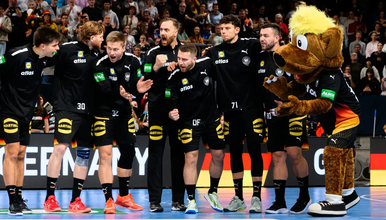Deutsche Handball-Männer-Nationalmannschaft steht in einer Reihe und jubelt sich zu.